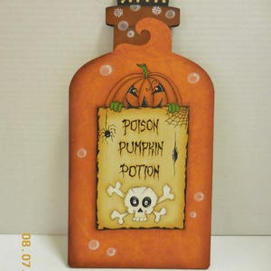 May include: Orange wooden bottle with a pumpkin face peeking out of the top. The bottle has a label that says "Poison Pumpkin Potion" with a skull and crossbones.