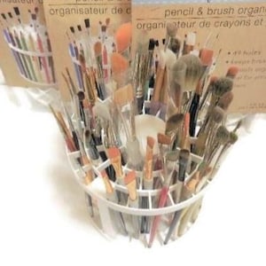 Op de afbeelding: Een witte, halfronde potlood- en penseelorganizer gevuld met diverse make-up penselen. De organizer heeft meerdere compartimenten en is ontworpen voor maximaal 49 items. De verpakking leest "pencil & brush organizer".