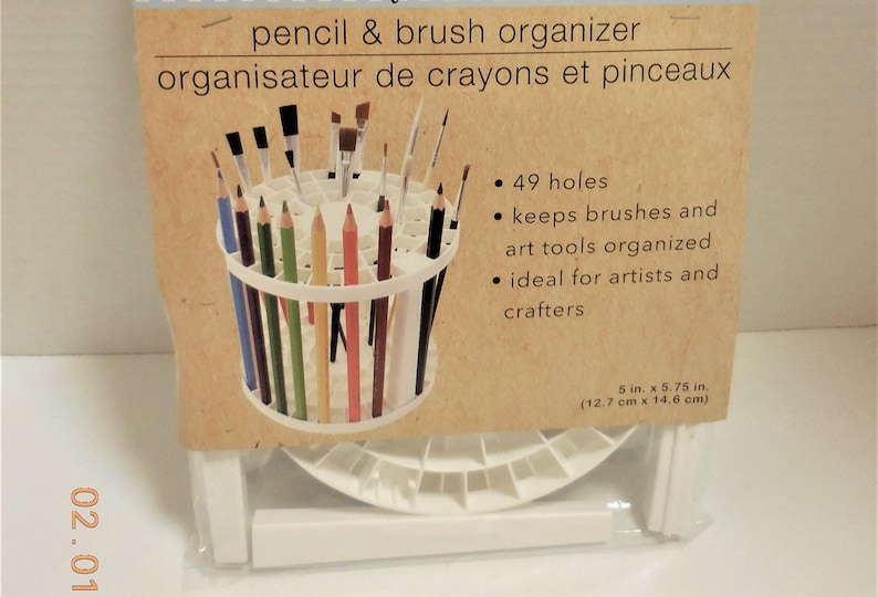 Op de afbeelding: Witte potlood- en penseelorganizer met een cilindrisch ontwerp, met diverse kleurpotloden en penselen. De verpakking leest "pencil & brush organizer" en bevat de afmetingen: 12,7 cm x 14,6 cm.