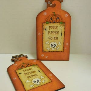 May include: Two orange wooden pumpkin potion bottles with a skull and crossbones and the text "Poison Pumpkin Potion" on a white background.