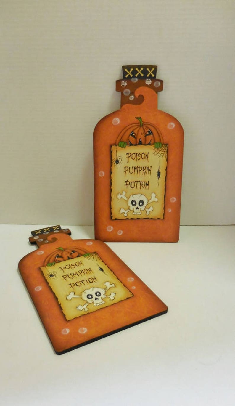 May include: Two orange wooden pumpkin potion bottles with a skull and crossbones and the text "Poison Pumpkin Potion" on a white background.