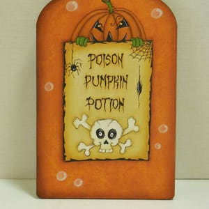 May include: Orange and brown painted wooden bottle with a pumpkin face and a sign that reads "Poison Pumpkin Potion" with a skull and crossbones.