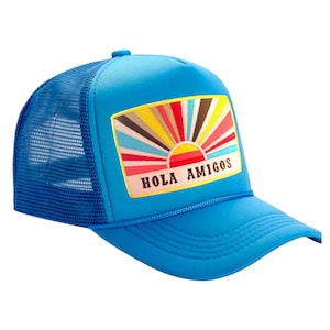 May include: A blue trucker hat with a colorful sunrise and "Hola Amigos" text on the front.