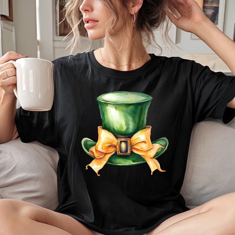 Puede incluir: Una camiseta negra con un sombrero verde de duende con un lazo naranja. El sombrero tiene una hebilla dorada.