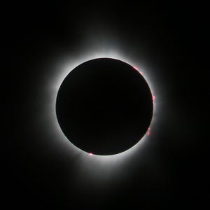 May include: A total solar eclipse, with the sun's corona visible as a bright ring around the moon's silhouette.