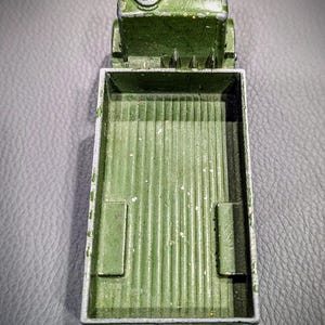 Puede incluir: Un cami&oacute;n de juguete verde con una plataforma. El cami&oacute;n es de metal y tiene un aspecto desgastado y envejecido. La plataforma est&aacute; vac&iacute;a.