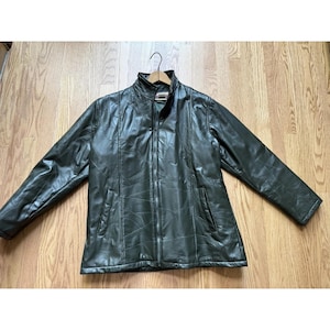 May include: Dark green leather jacket with a full-length zipper, two front pockets, and a stand-up collar. The jacket is hanging on a wooden hanger. The jacket is made of a patchwork design.