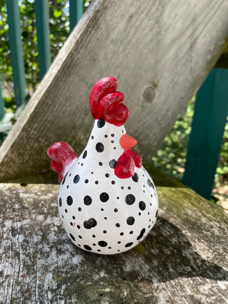 May include: A white ceramic chicken figurine with black polka dots and a red comb and wattle.