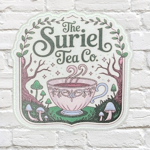 May include: A sticker featuring the text "The Suriel Tea Co." above a teacup with steam rising from it. The design includes trees, mushrooms, and decorative elements in shades of pink, green, and brown.