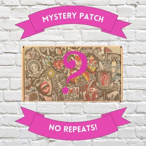 Op de afbeelding: Een kartonnen doos gevuld met diverse patches, met een groot roze vraagteken. De doos is versierd met patches van verschillende ontwerpen en kleuren. Roze banners boven en onderaan lezen "MYSTERY PATCH" en "NO REPEATS!"