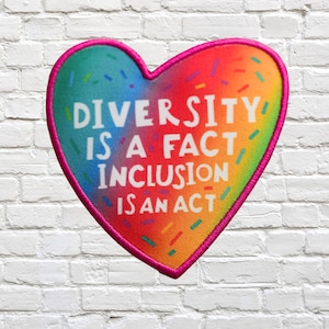 Może przedstawiać: Naszywka w kształcie tęczowego serca z tekstem "Różnorodność to fakt, inkluzja to działanie".
