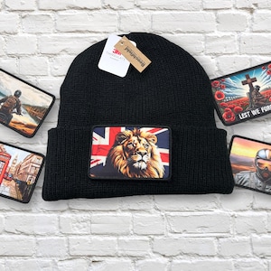 Könnte beinhalten: Schwarze Strickmütze mit einem rechteckigen Aufnäher mit einem Löwen und dem Union Jack. Zusätzliche Aufnäher zeigen einen Motorradfahrer, eine Londoner Szene, einen Piloten und ein Kriegerdenkmal mit dem Text "Lest We Forget".