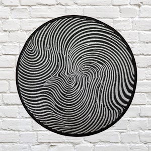 Op de afbeelding: Een ronde, zwart-witte patch met een wervelend, hypnotiserend ontwerp. Het patroon bestaat uit talrijke gebogen lijnen, die een visuele vortex creëren. De patch is waarschijnlijk voor kleding of accessoires.