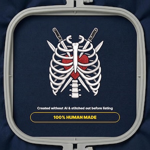 Puede incluir: Un diseño de bordado en un bastidor gris sobre tela azul oscuro con una caja torácica y columna vertebral blancas rodeando un corazón rojo, con dos dagas cruzadas detrás. Texto: Created without AI & stitched out before listing 100% HUMAN MADE.