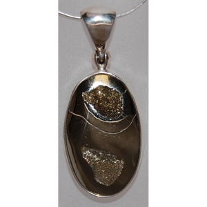 Puede incluir: Colgante ovalado con una fianza y cadena de color plateado. El colgante presenta una piedra pulida de color oscuro con dos secciones de cristales dorados brillantes. El colgante mide aproximadamente 3,8 cm de largo.