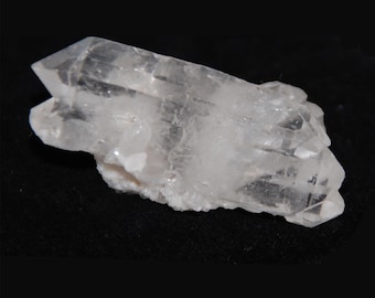 Könnte beinhalten: Ein klarer Quarzkristall-Cluster mit mehreren Spitzen, der eine natürliche, rohe Formation zeigt. Der Kristall ist auf einem dunklen Hintergrund platziert.