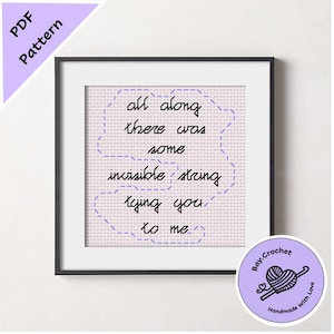 May include: Framed cross-stitch art with the quote "all along there was some invisible string tying you to me." The artwork is in a black frame with a light purple background and a circular logo in the bottom right corner.