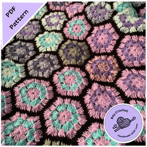 May include: A crochet blanket with a hexagonal pattern in shades of pink, purple, blue, and green. The blanket is made with a textured stitch that creates a raised, puffy effect. The blanket is edged with a black border.