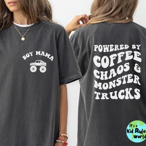 May include: Dark grey t-shirt with white text and graphics. The front says "Boy Mama" with a monster truck graphic. The back says "Powered by Coffee Chaos & Monster Trucks". A Kid Ruled World logo is on the bottom right.