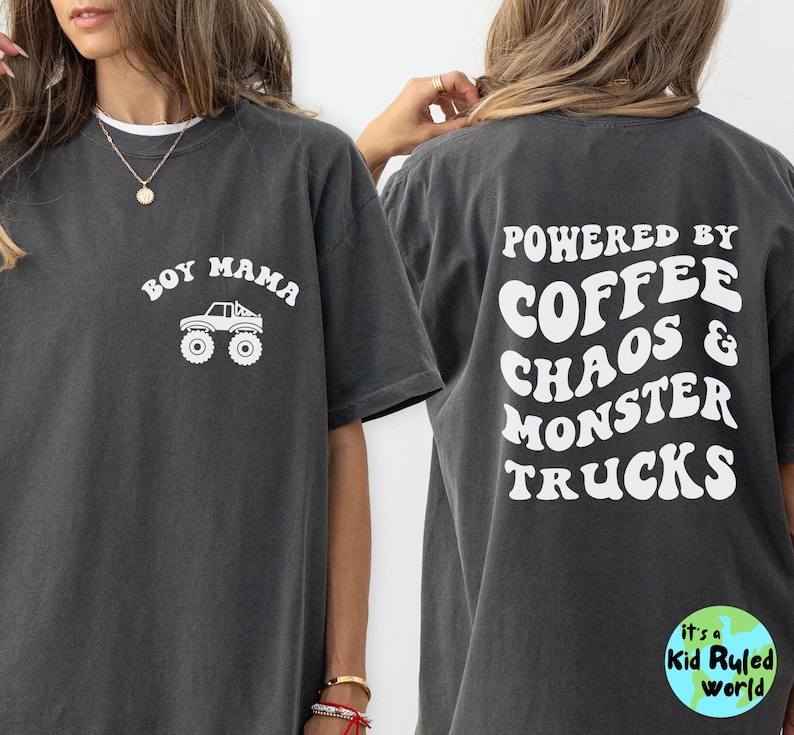 May include: Dark grey t-shirt with white text and graphics. The front says "Boy Mama" with a monster truck graphic. The back says "Powered by Coffee Chaos & Monster Trucks". A Kid Ruled World logo is on the bottom right.