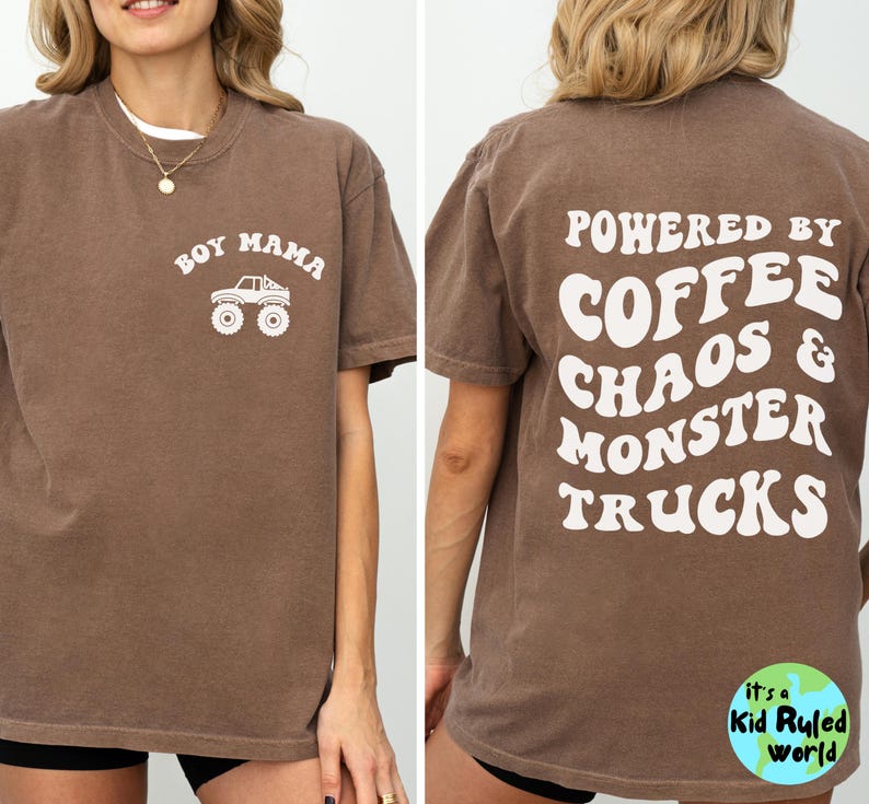 May include: Brown t-shirt with white text and graphics. The front says "BOY MAMA" above a monster truck graphic. The back says "POWERED BY COFFEE CHAOS & MONSTER TRUCKS". A small logo is at the bottom.