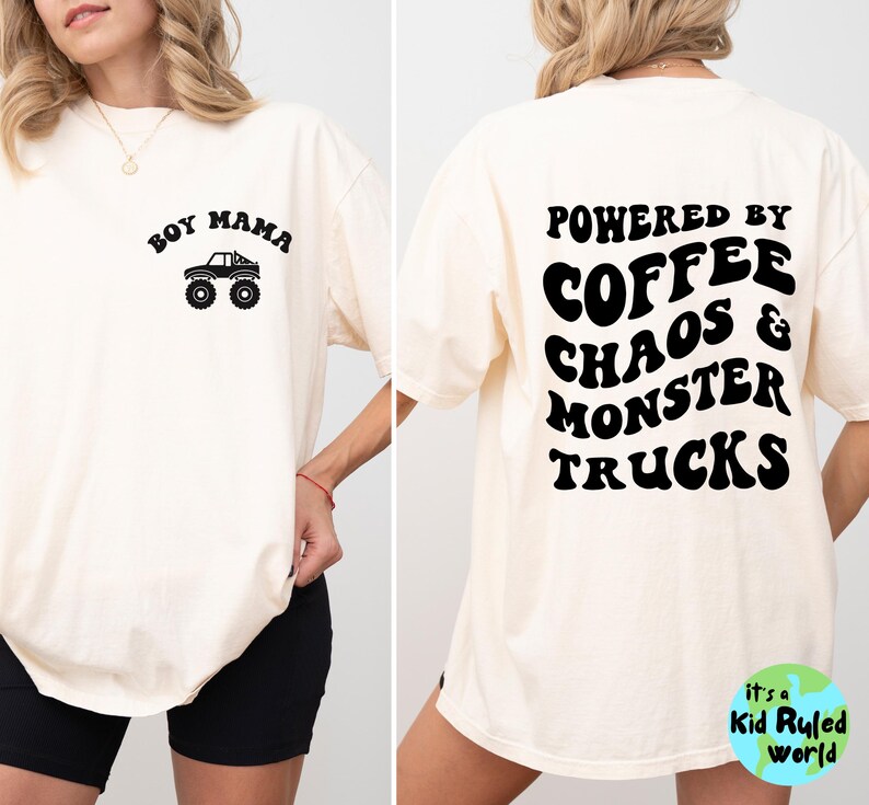 May include: A cream-coloured t-shirt featuring black text and graphics. The front displays "Boy Mama" above a monster truck illustration. The back reads "Powered by Coffee Chaos & Monster Trucks". Part of the "Kid Ruled World" collection.