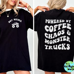 May include: Black t-shirt with white text and graphics. The front reads "Boy Mama" with a monster truck graphic. The back says "Powered by Coffee Chaos & Monster Trucks". A fun, casual tee.