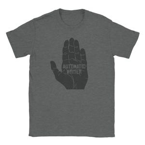 May include: A dark heather gray t-shirt with a black silhouette of a hand with the text "Automatic Writer" printed on the palm.