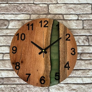 May include: A wooden wall clock with a green epoxy resin inlay. The clock face has black numbers and hands.