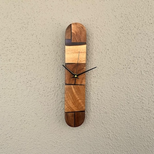 Könnte beinhalten: Eine Holzuhr mit geometrischem Design, die verschiedene Brauntöne von Holz zeigt. Die Uhr hat schwarze Zeiger und ein goldenes Zentrum.