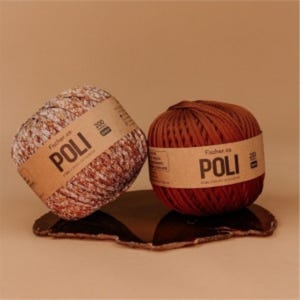 May include: Two balls of yarn with labels that read "POLI" in a serif font. One ball is a mix of brown and white, the other is a solid reddish-brown. The yarn balls are resting on a dark, irregular-shaped surface.