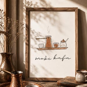 May include: A framed print with a coffee-themed illustration. The artwork depicts a coffee pot, cups, and a sugar bowl on a tray, with the text "może kafa" below. The frame is brown, and the overall color scheme is warm and inviting.