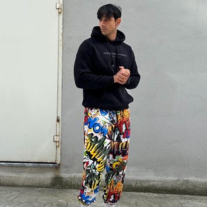 K&ouml;nnte beinhalten: Eine Person tr&auml;gt einen schwarzen Hoodie mit dem Text "making mistakes is common but making the same mistake twice is a choice" und eine bunte Hose mit grafischem Druck. Die Person tr&auml;gt wei&szlig;e Sneaker.