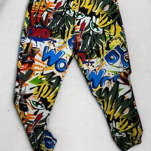 K&ouml;nnte beinhalten: Schwarz, wei&szlig;, blau, gelb, gr&uuml;n und rot bedruckte Hose mit Comic-Design. Die Hose hat einen Kordelzugbund und eine lockere Passform.