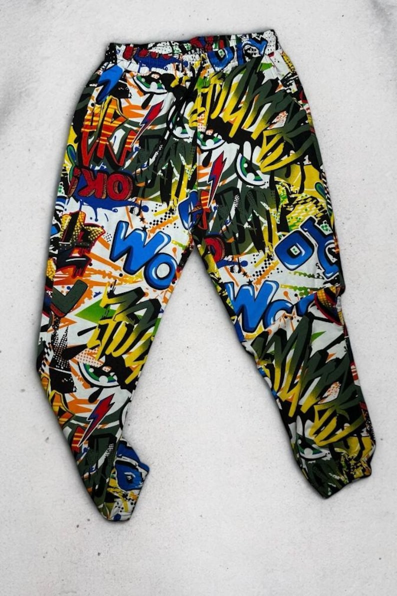 K&ouml;nnte beinhalten: Schwarz, wei&szlig;, blau, gelb, gr&uuml;n und rot bedruckte Hose mit Comic-Design. Die Hose hat einen Kordelzugbund und eine lockere Passform.
