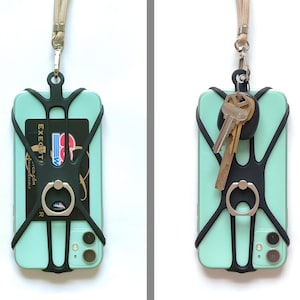 May include: A black phone case with a built-in ring holder and a black strap. The case is attached to a phone with a light green back and a black camera lens. The strap is attached to a key ring with two keys.