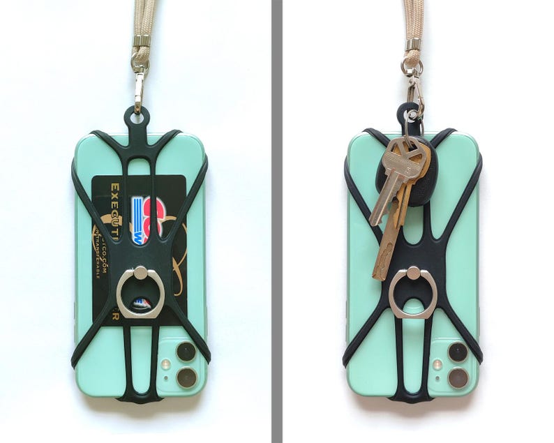 May include: A black phone case with a built-in ring holder and a black strap. The case is attached to a phone with a light green back and a black camera lens. The strap is attached to a key ring with two keys.