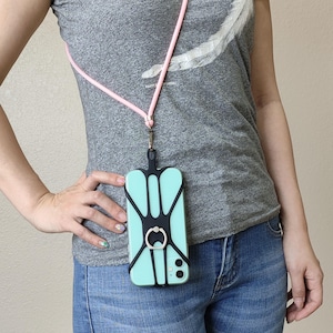 May include: A black phone case with a built-in ring holder and a pink lanyard. The case is attached to a phone with a light blue screen.
