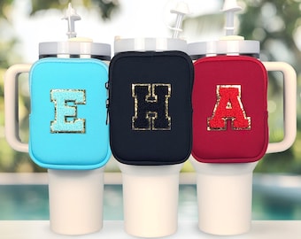 Puede incluir: Tres fundas aislantes para tazas en azul, negro y rojo con letras E, H y A de purpurina dorada. Las fundas están diseñadas para ajustarse alrededor de una taza de viaje o un vaso.
