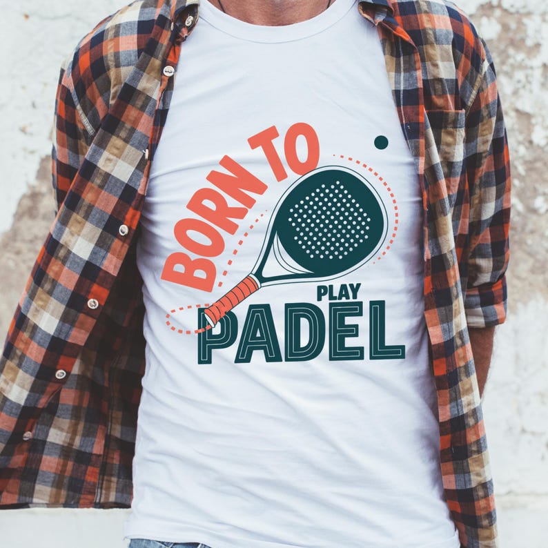May include: White t-shirt with a padel racket graphic and the text "BORN TO PLAY PADEL" in orange and teal. The shirt has a crew neck and is worn with a plaid button-down shirt.