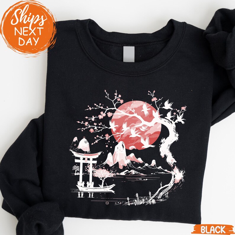 A black sweatshirt with a graphic design depicting a cherry blossom tree with a large red moon in the background.