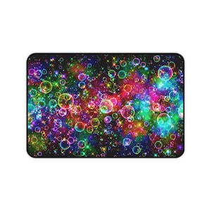 May include: Rectangular mousepad featuring a vibrant, colorful design of overlapping bubbles and sparkling stars. The background is a mix of pink, purple, blue, and green hues, creating a whimsical and eye-catching pattern. The mousepad has a black border.