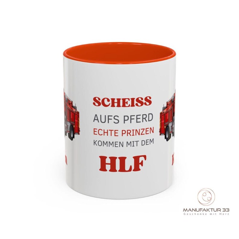 May include: White ceramic mug with an orange interior, featuring red text and a red fire truck graphic. The text reads "SCHEISS AUFS PFERD ECHTE PRINZEN KOMMEN MIT DEM HLF". A logo is visible on the bottom right.