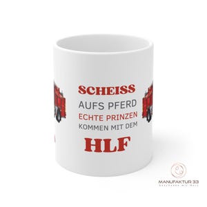 May include: White ceramic mug with the text "SCHEISS AUFS PFERD ECHTE PRINZEN KOMMEN MIT DEM HLF" in red. The mug features a red fire truck graphic on each side. The bottom right corner has a logo.