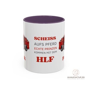 May include: White ceramic mug with a purple interior and a red fire truck design. The mug features the text "SCHEISS AUFS PFERD ECHTE PRINZEN KOMMEN MIT DEM HLF". The mug has a glossy finish.