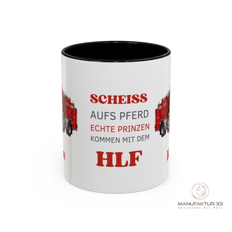 May include: White ceramic mug with a black interior and a red fire truck graphic. The mug features red text that reads "SCHEISS AUFS PFERD ECHTE PRINZEN KOMMEN MIT DEM HLF". The mug has a glossy finish.