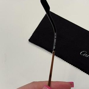 May include: A gold metal eyeglass arm with a black plastic tip. The arm is engraved with the text 'Made in Italy'.