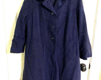 May include: A long, navy blue wool coat with a collar and four buttons down the front. The coat has two pockets on the front.