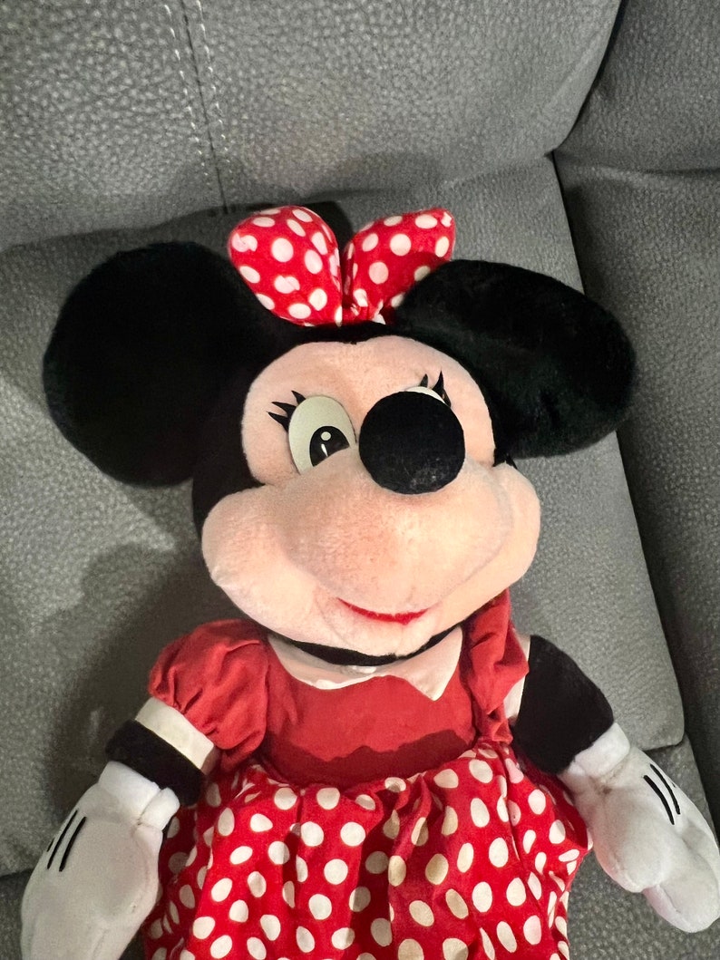 K&ouml;nnte beinhalten: Ein Pl&uuml;schtier von Minnie Mouse, das ein rotes Kleid mit wei&szlig;en Punkten und eine rote Schleife mit wei&szlig;en Punkten tr&auml;gt.