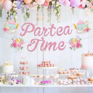 Pode incluir: Uma faixa decorativa com o texto "Partea Time" em glitter rosa suspensa sobre uma mesa de sobremesas. A faixa é decorada com ilustrações de bules em tons pastel e buquês de rosas cor-de-rosa, amarelas e brancas em cada lado.